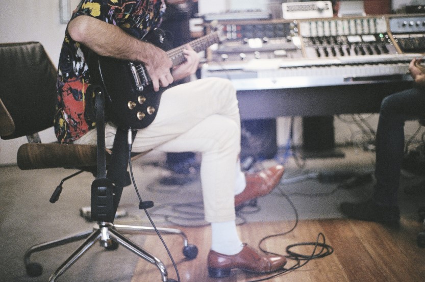 man recording electric guitar in studio