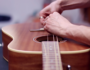 A person changing acoustic guitar strings, carefully replacing old strings with new ones while tuning the guitar for optimal sound quality.