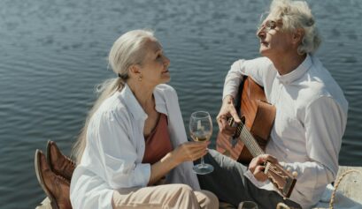 Couple sitting on the beach, playing love songs on guitar
