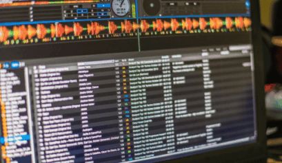 Computer screen showing DJ software with track list and audio visualizations.