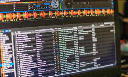 Computer screen showing DJ software with track list and audio visualizations.