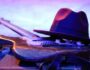 Mississippi Delta Blues guitar resting on stage with hat under colorful concert lights
