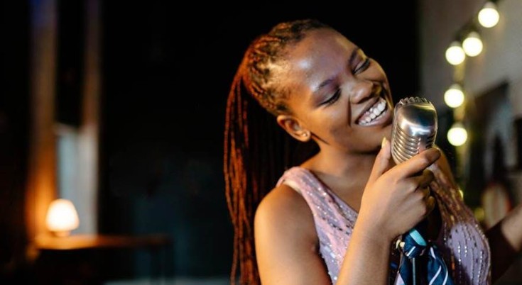 Singer practicing vocals with microphone during a remote or in-person singing lesson session.