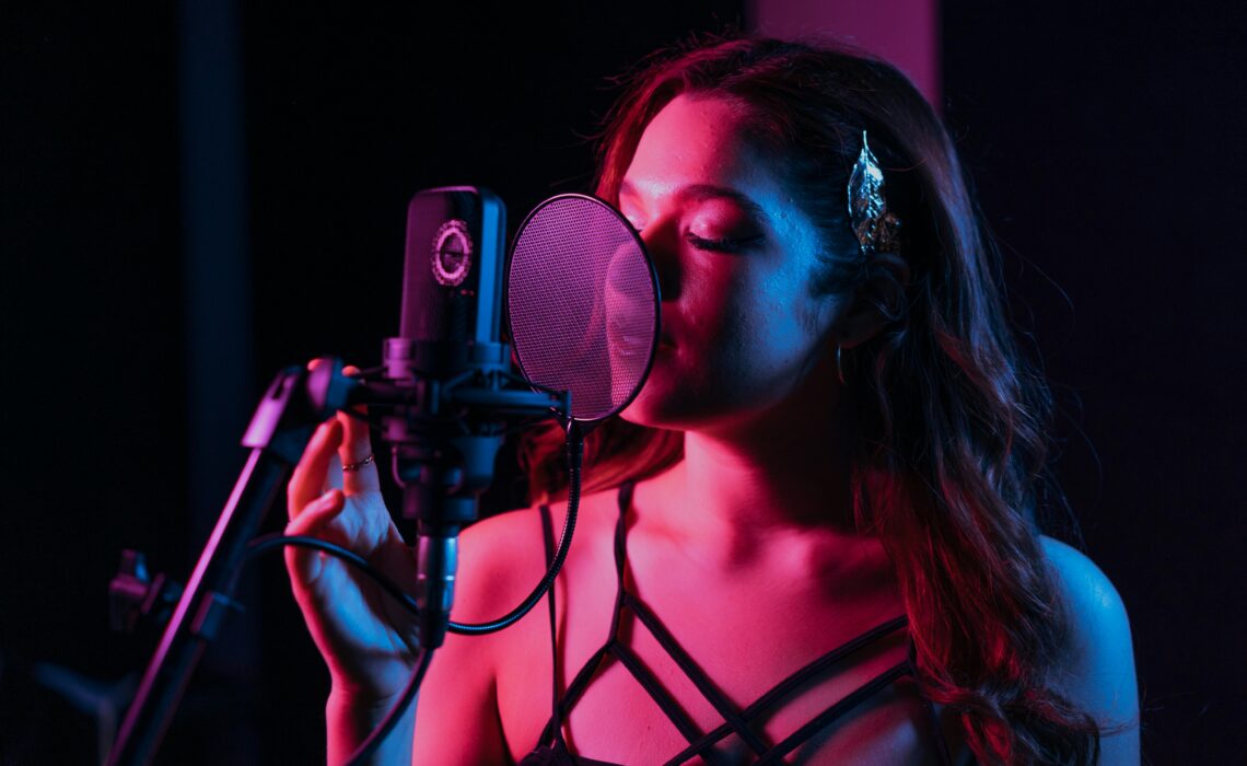 Voice type singing training: female singer recording vocals in studio with microphone