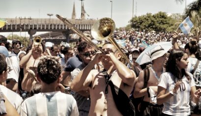 Argentina supporters playing brass instruments and singing during a football celebration, highlighting the role of music in football culture.
