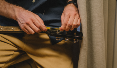 Musician replacing guitar strings while tuning an acoustic guitar.