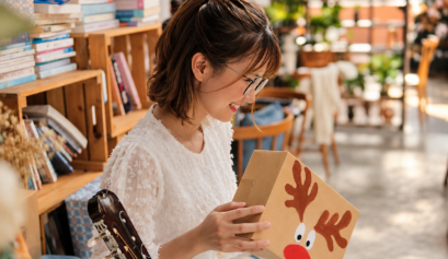 Female guitarist smiling as she opens a Christmas gift box, capturing the joy of receiving a thoughtful gift for a musician.
